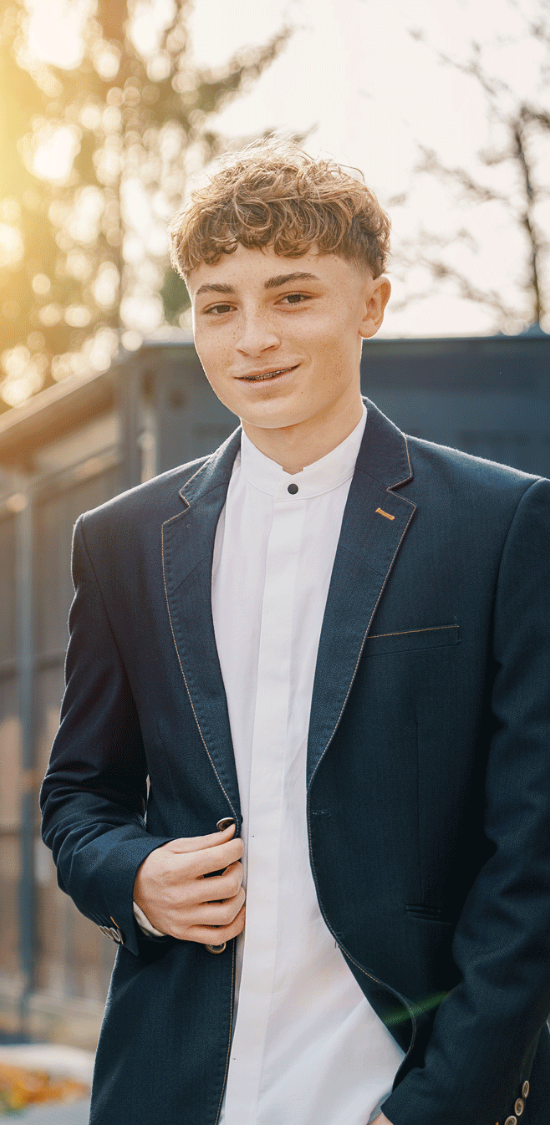 Mann in blauem Trenchcoat und Jeans, posiert vor neutralem Hintergrund.